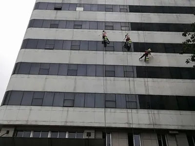 南京住建委大楼外立面防水施工，三名作业人员乘吊篮在高层外墙作业