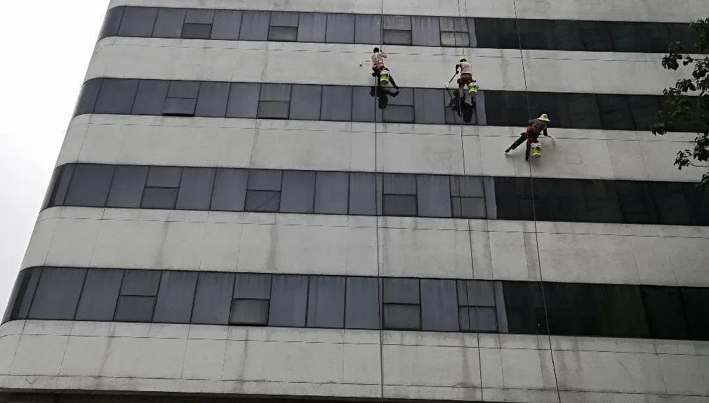 南京住建委大楼外立面防水施工，三名作业人员乘吊篮在高层外墙作业